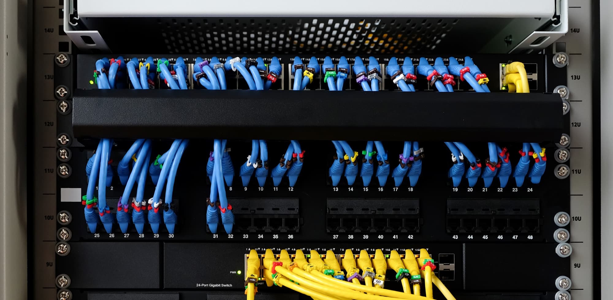 Bundle of fibre optic network cables routed through a server rack in a data centre