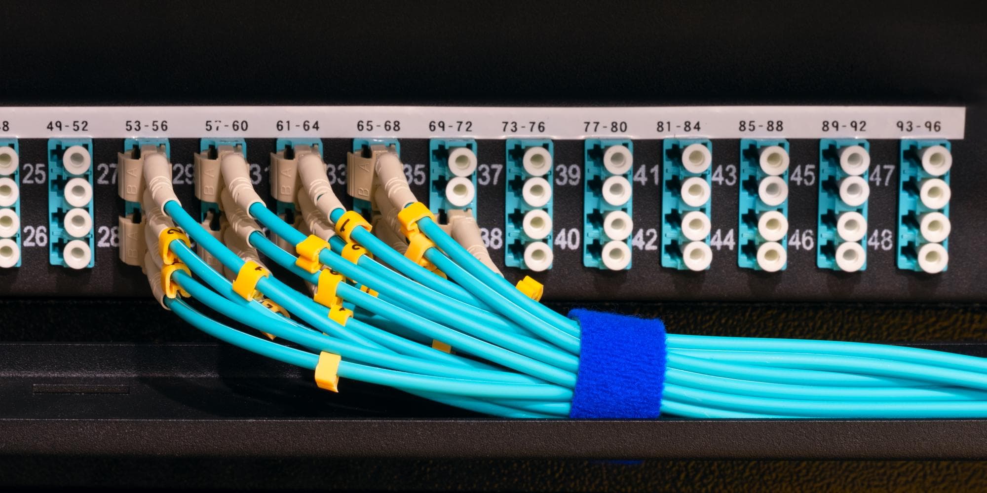 Two server racks side by side in a cool data centre with fibre optic cables and status LEDs