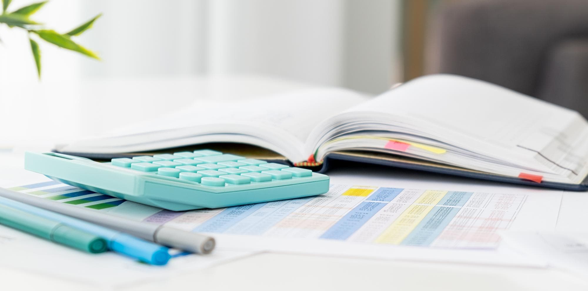 Office desk with a blank notepad, pen on top, and a laptop to one side