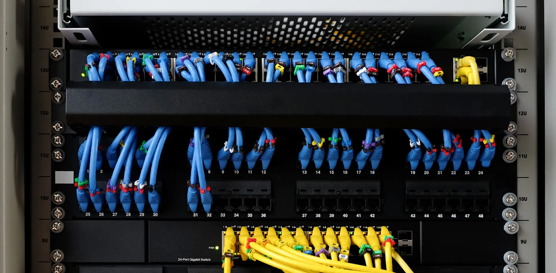 Bundle of fibre optic network cables routed through a server rack in a data centre