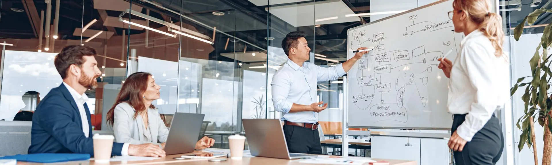 Two people standing at a flipchart in a bright office conducting a meeting and walking colleagues through a strategy diagram