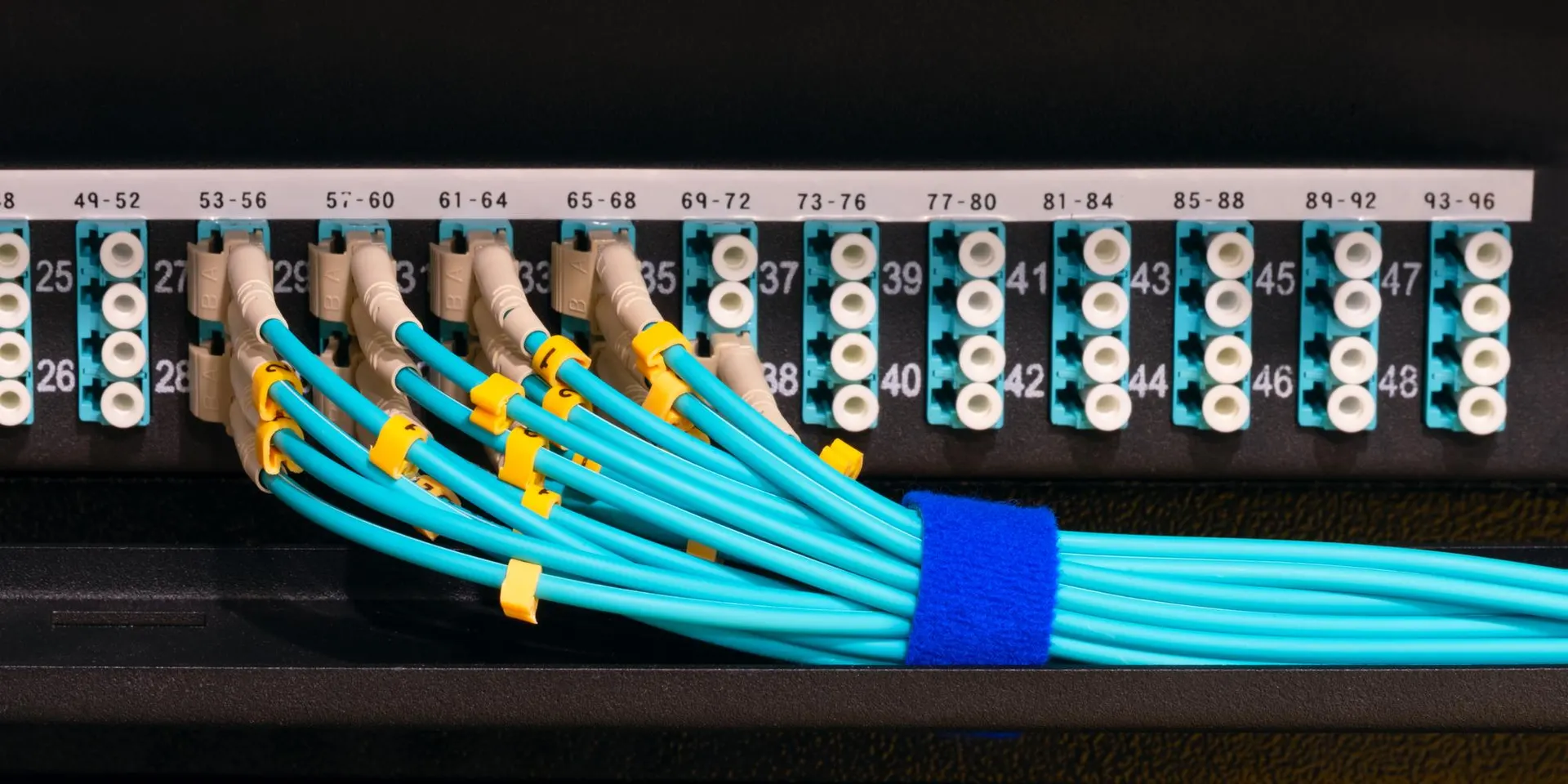 Two server racks side by side in a cool data centre with fibre optic cables and status LEDs