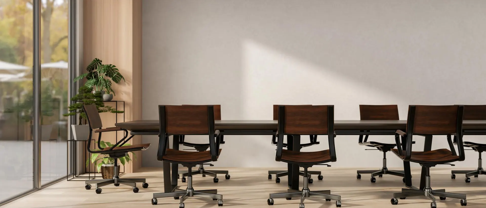 Two empty boardroom chairs facing each other across a wood table, soft window light, an open laptop on the table between them